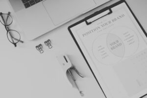 Brand strategy worksheet on a clean workspace with glasses, laptop and office tools, showing a positioning diagram.