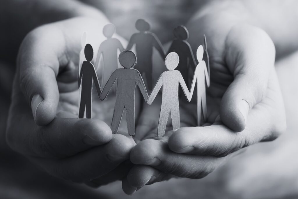 Small paper figures standing together in an open hand, representing collaboration, support, and shared direction.